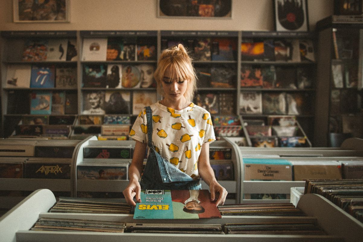 blonde girl at vintage record store with blue jean overalls