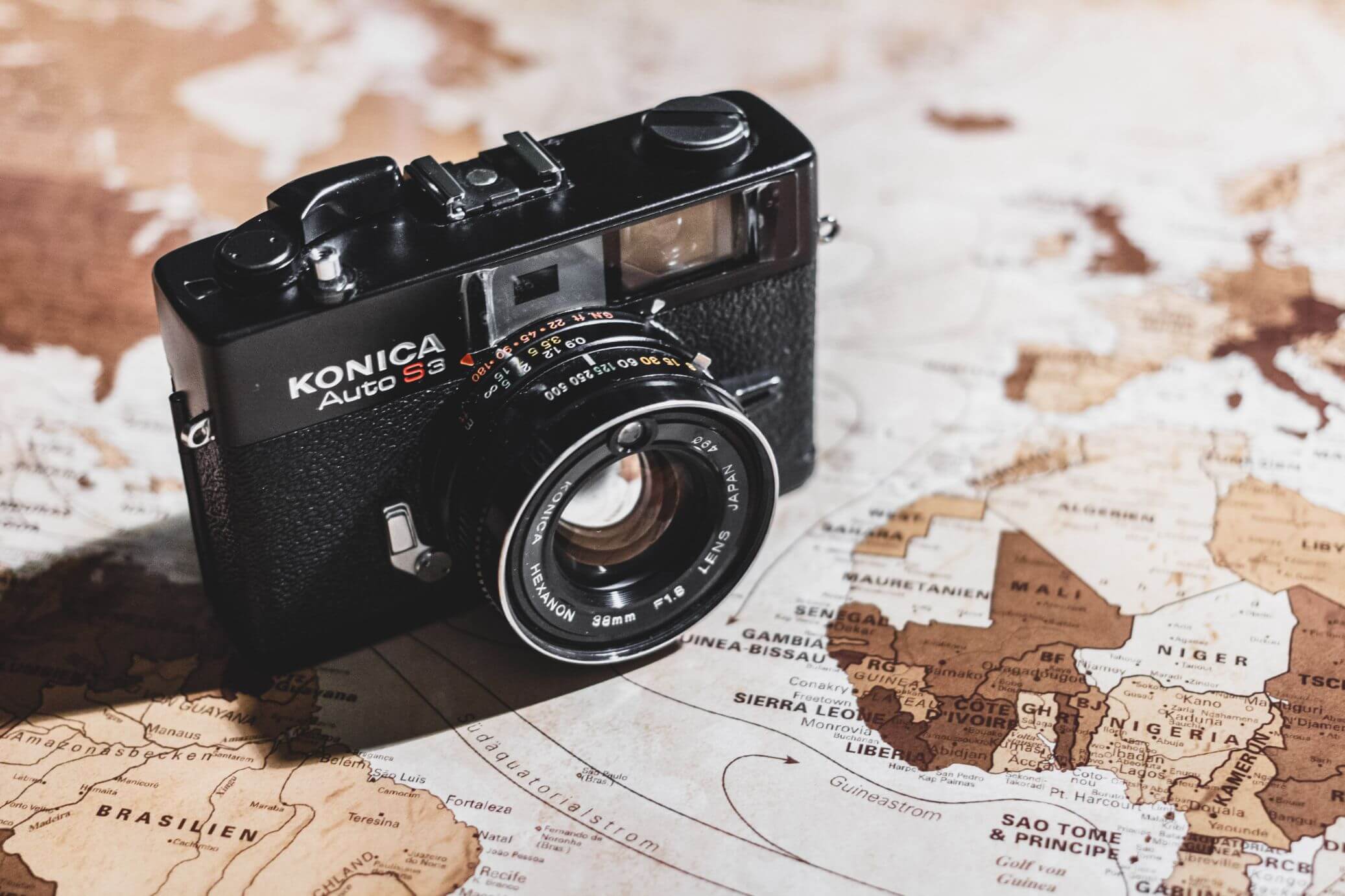 world map with vintage film camera on top